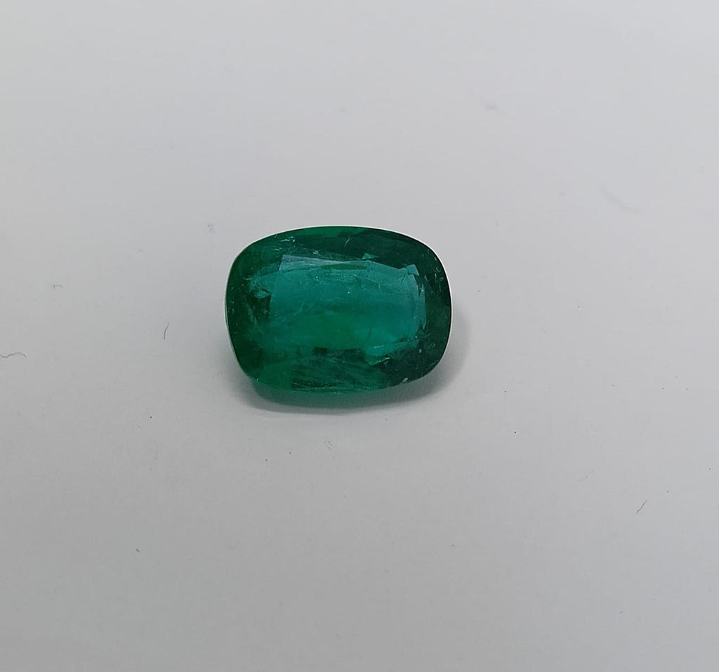 Cushion-shaped emerald on a light gray background